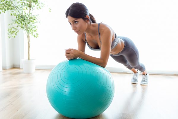 Beautiful young woman doing pilate exercise with fitness ball at